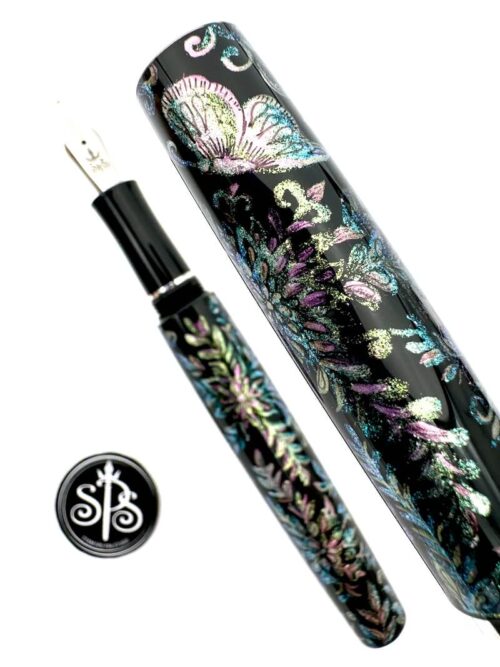 Close-up of the cap of a hand-painted pen showing a butterfly and foliage in colour-shift paints. The pen barrel and nib are in the background.